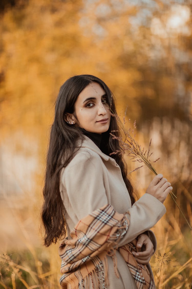 Attractive Young Woman With Long Black Hair Standing In Field Of Grass