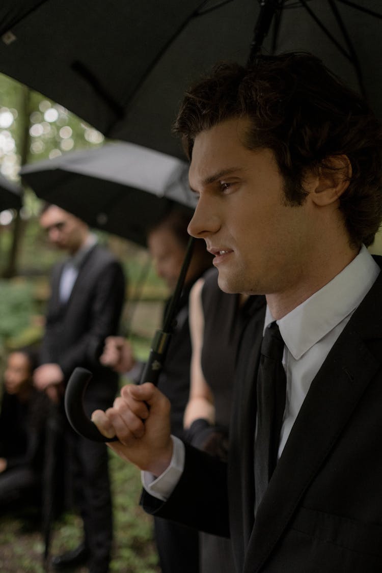 Man In Black Suit Holding A Black Umbrella