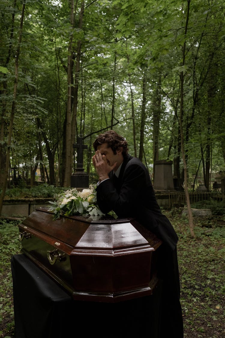 Grieving Man Crying Beside The Coffin