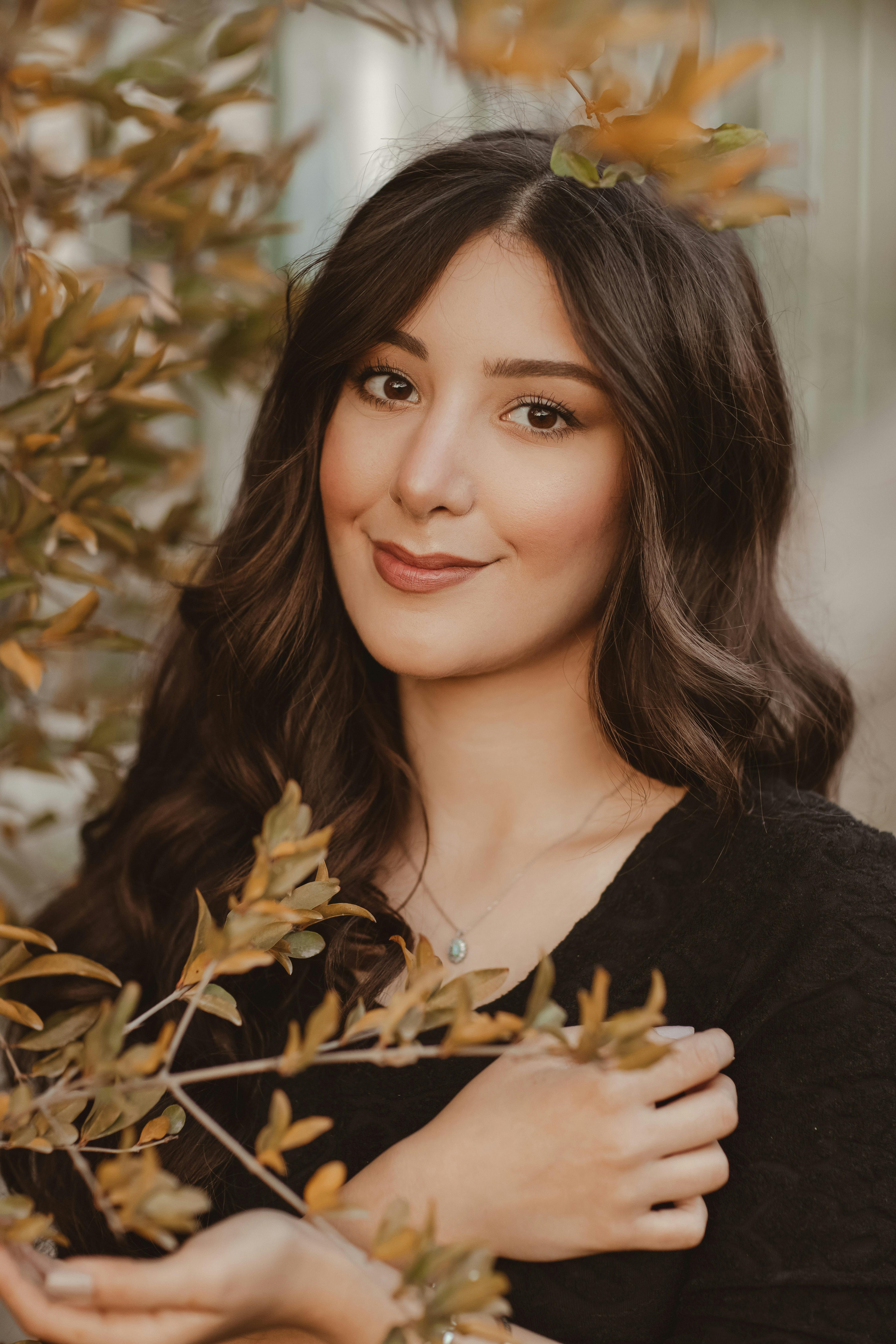 smiling face of nice brunette woman standing by plant with yellow leaves