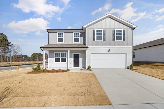 A modern two-story suburban house with a garage under a blue sky.