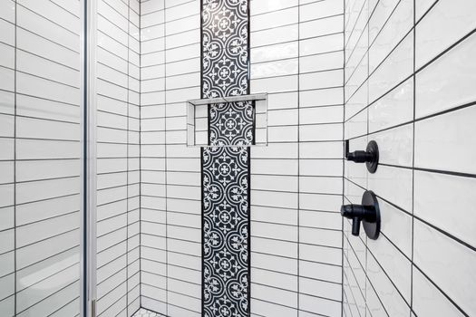 Stylish shower area featuring black and white geometric tiles and contemporary fixtures.
