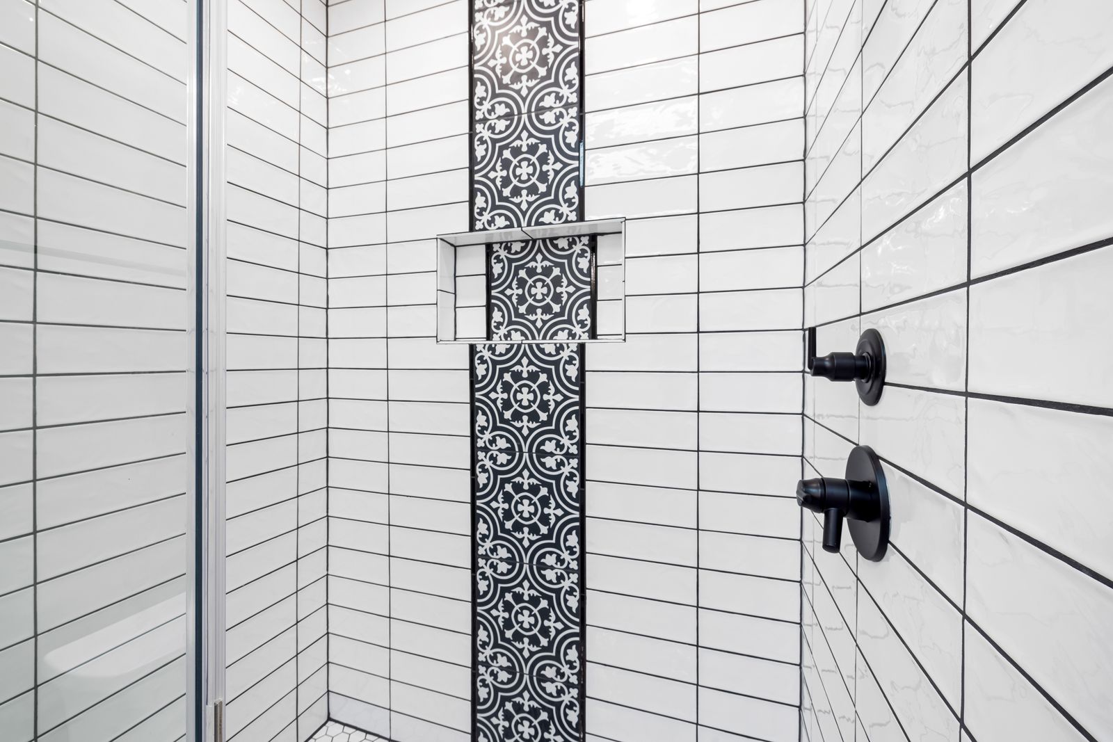 Bathroom shower area featuring graphic black-and-white geometric tile.