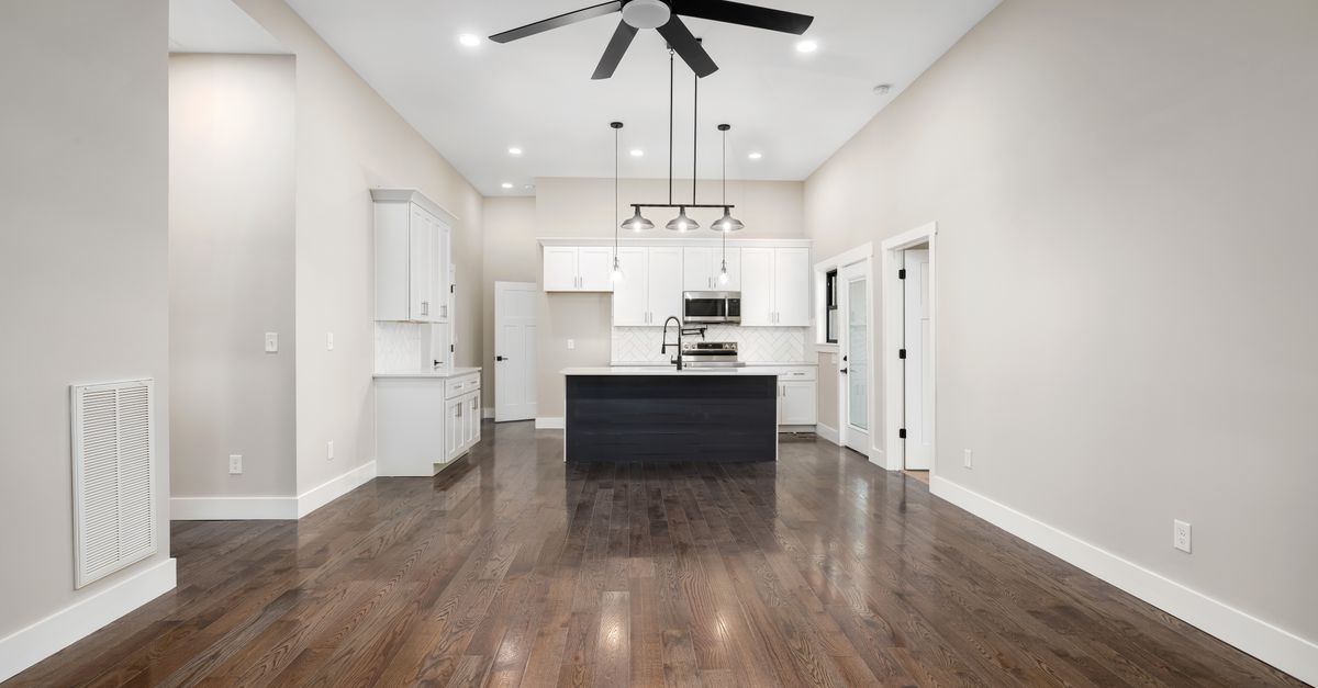 Spacious modern kitchen featuring hardwood floors, ceiling fan, and sleek cabinetry, perfect for interior design inspiration.
