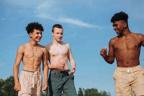 Free Three diverse teenage boys having fun in the summer sun, smiling and enjoying time outdoors. Stock Photo