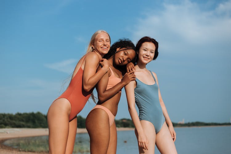 Girls Standing Next To Each Other On The Beach