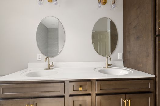 Modern bathroom vanity featuring dual sinks with oval mirrors and stylish fixtures. Perfect for home decor inspiration.