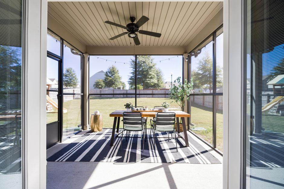 A bright and inviting terrace with dining table and chairs, overlooking a sunny garden.