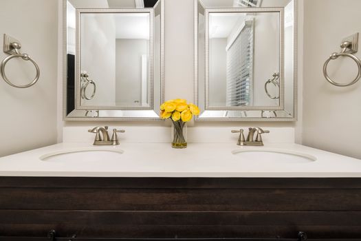 Elegant modern bathroom with twin mirrors, stylish faucets, and a touch of luxury with yellow flowers.