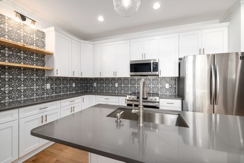 Free Stylish white kitchen featuring a geometric tile backsplash and stainless steel appliances. Stock Photo