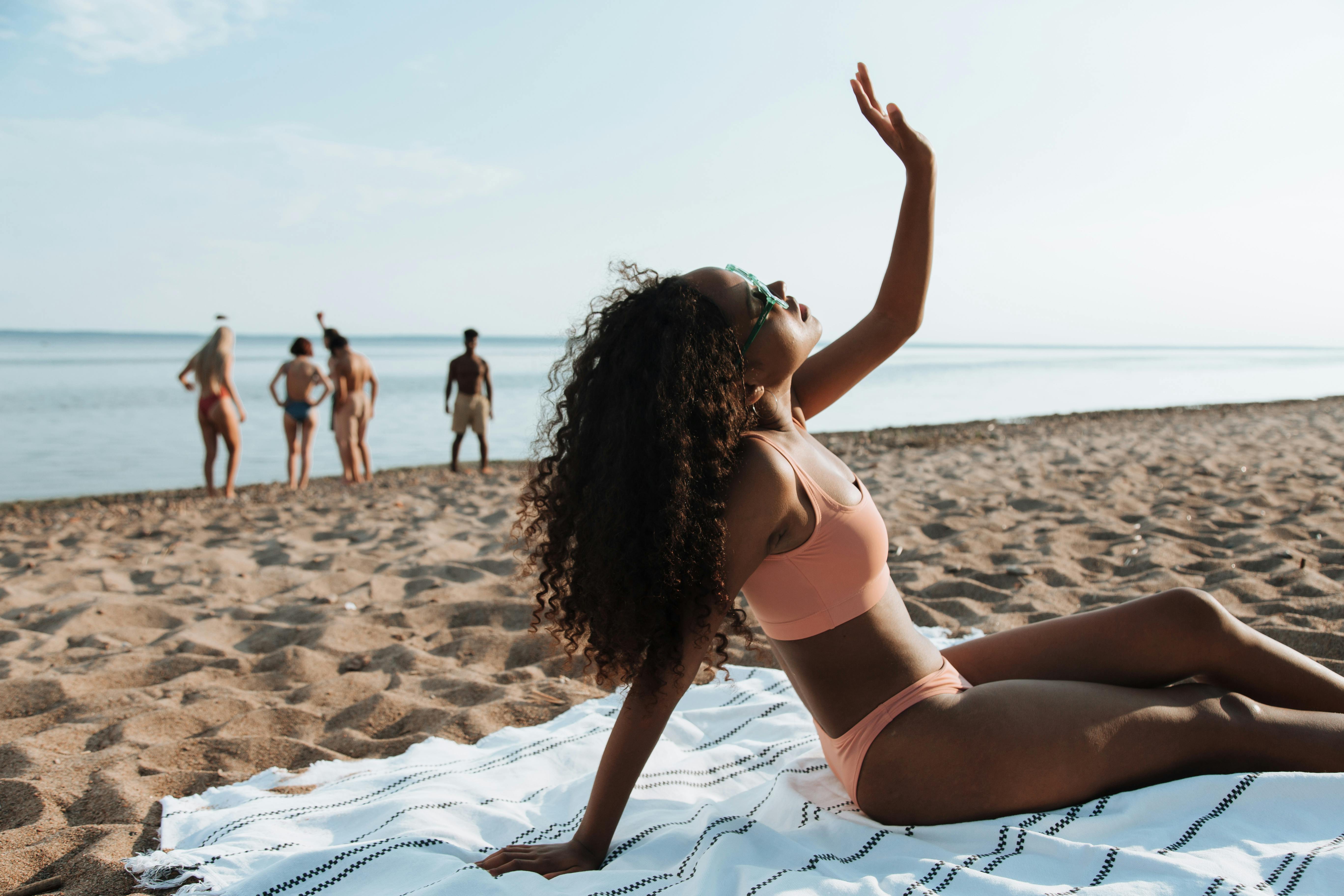 a woman in a bikini sitting at a beach