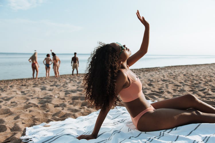 A Woman In A Bikini Sitting At A Beach