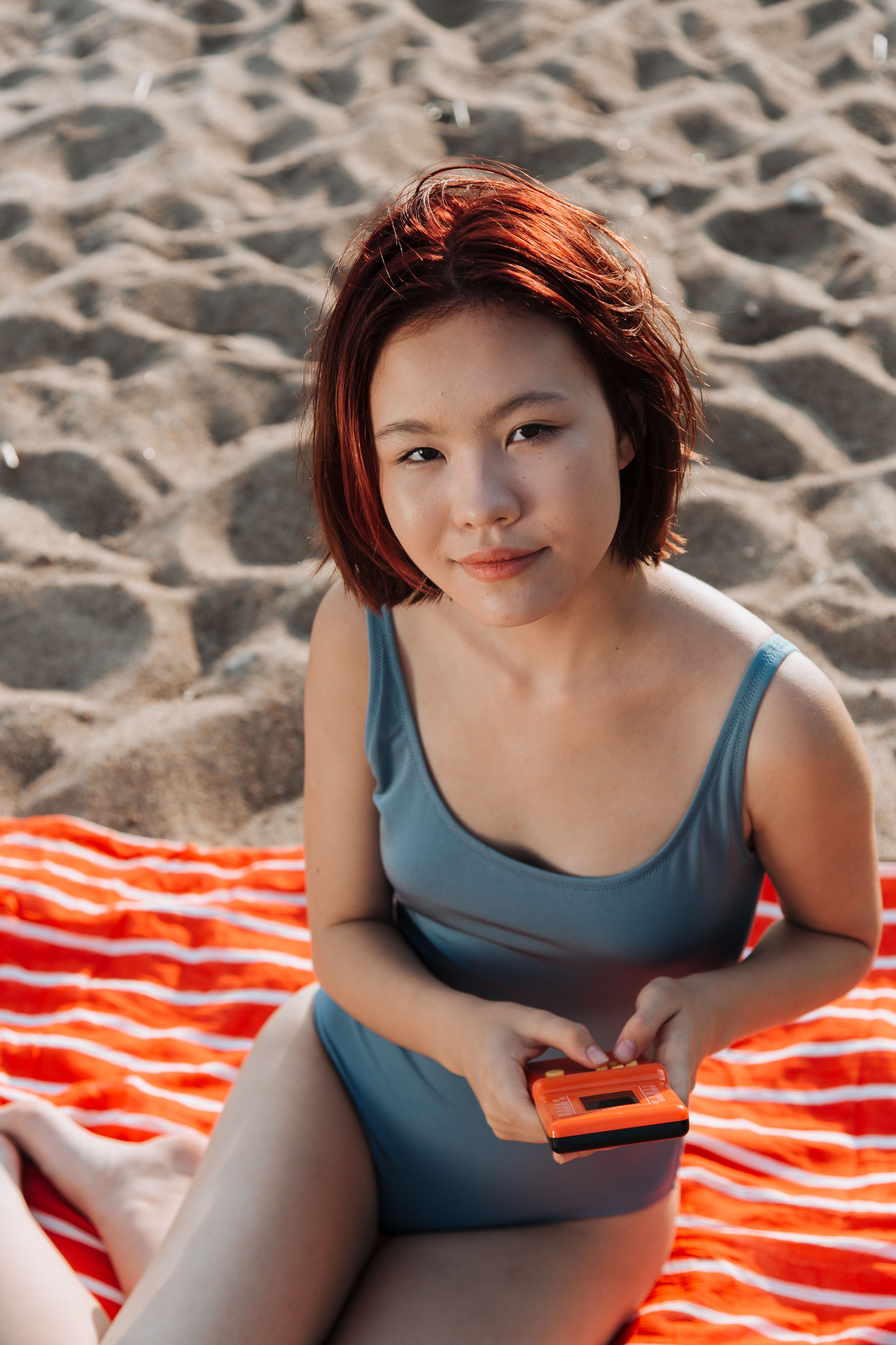Smiling woman on a towel at the beach enjoying a sunny day.