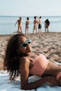 年轻女子戴着太阳镜在海滩上晒日光浴，享受夏日时光