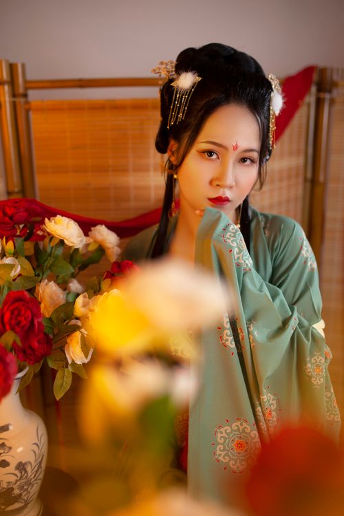 Free Portrait of a woman in traditional outfit with vibrant floral background and stylish hairpiece. Stock Photo