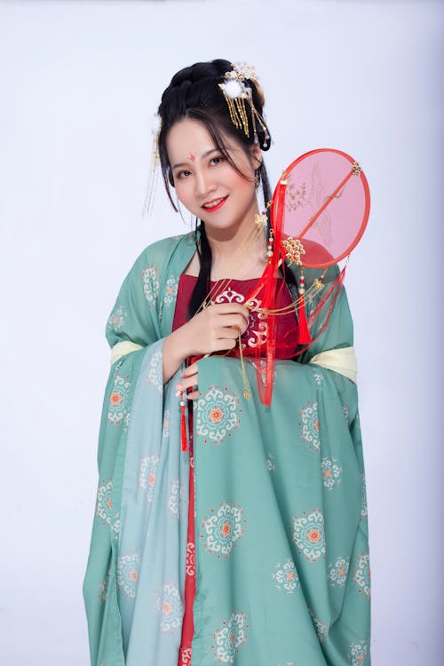 Woman in Traditional Dress Holding a Hand Fan