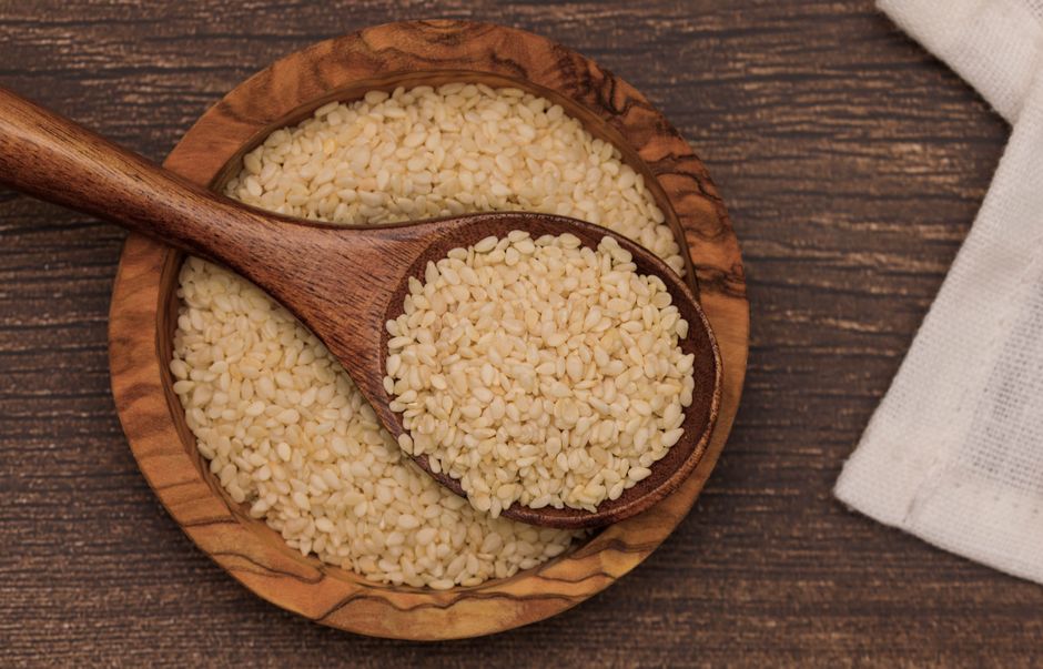 A wooden bowl and spoon filled with hulled sesame seeds, the seed pressed for sesame oil. Photo by Victoria Bowers on Pexels