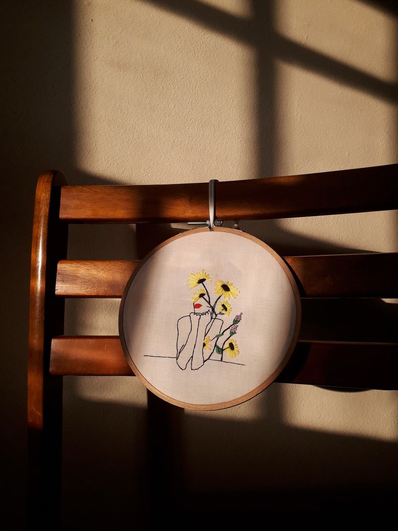Line-art sunflower hoop stitched in golden thread