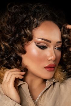 Close-up portrait of a woman with curly hair and striking makeup.