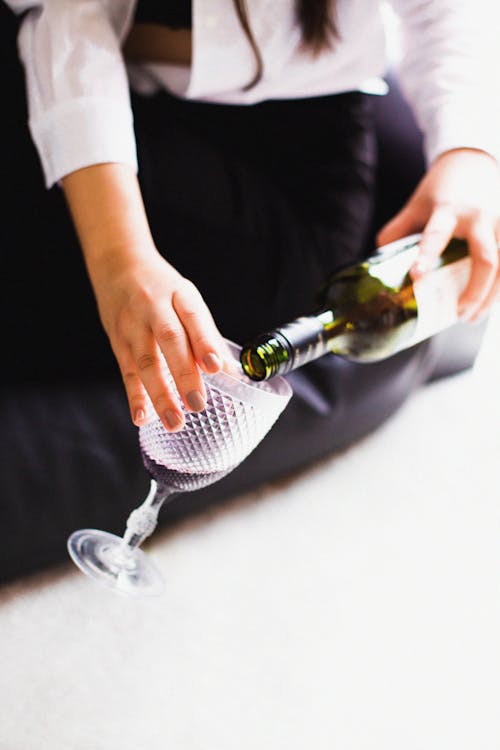 Close-Up Shot of a Person Pouring Wine on a Glass