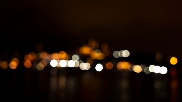 Blurred city lights creating a bokeh effect on a dark evening skyline.