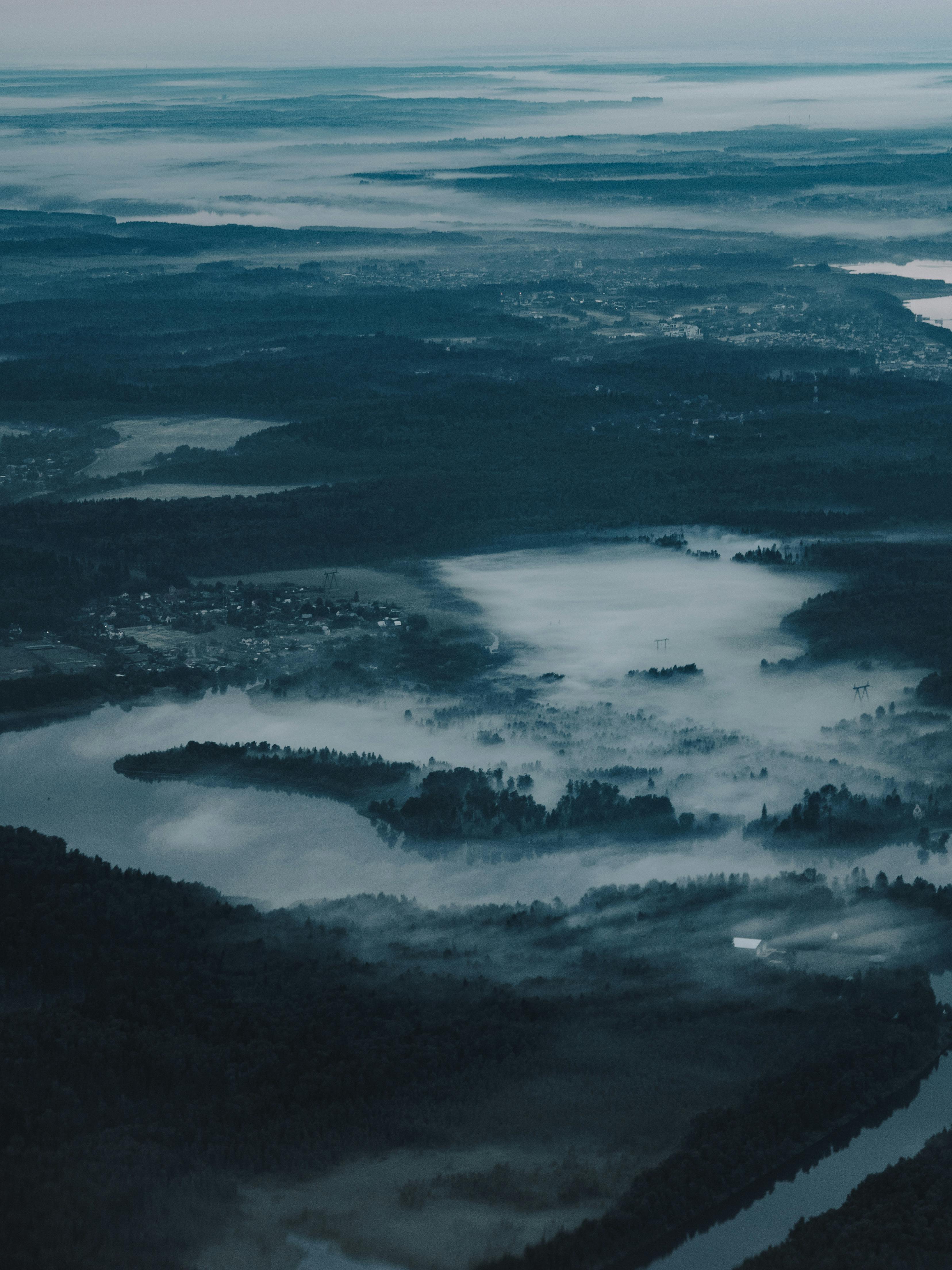 Explore a serene aerial view of a mist-covered forest and lake, capturing the essence of tranquility.