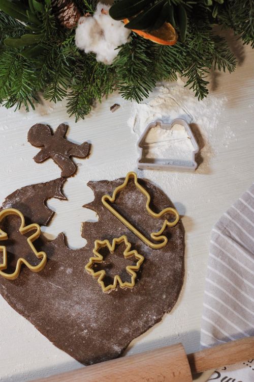 Free Overhead view of Christmas cookie cutters on chocolate dough with festive decorations. Stock Photo