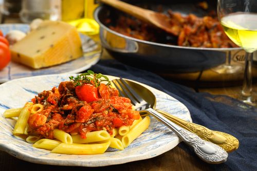 Free Mouthwatering penne pasta topped with rich tomato sauce and herbs on a ceramic plate. Stock Photo