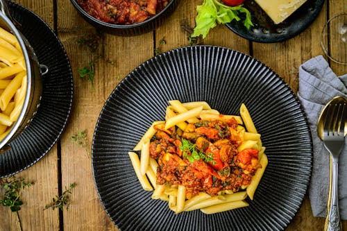 Free Penne Pasta with Red Sauce on Black Round Plate Stock Photo