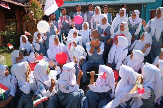 Group of Indonesian students and teacher celebrating an outdoor school event.