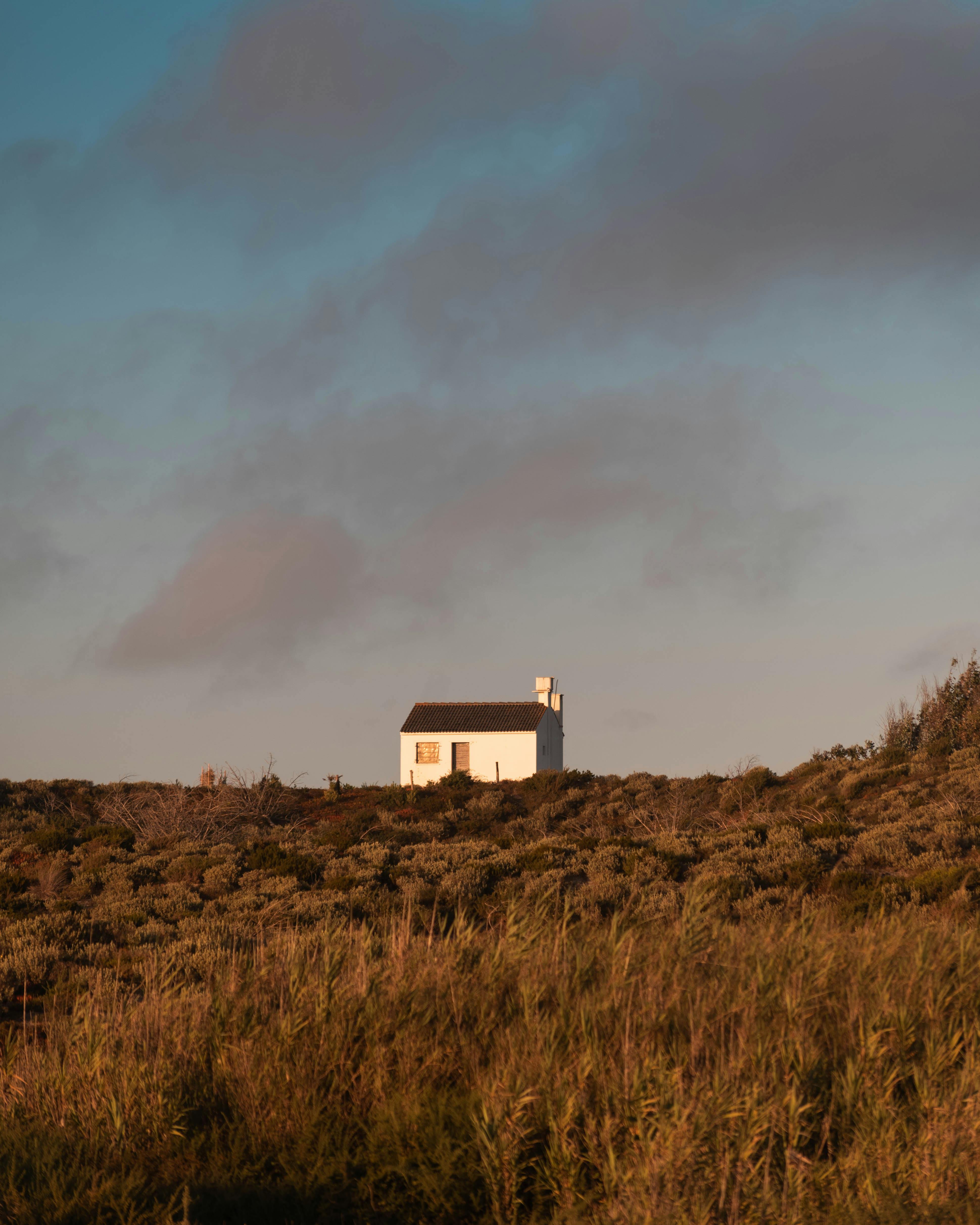 A quaint white house sits amidst a lush, green landscape under a cloudy sky in rural Portugal.