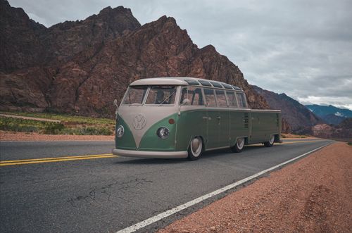 Free A classic Volkswagen bus driving through a picturesque mountain landscape, evoking a sense of nostalgia and adventure. Stock Photo