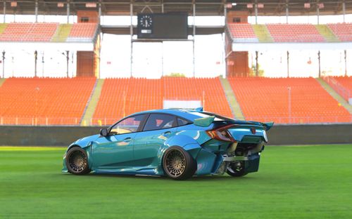 Free A sleek blue sports car on a green field in an empty stadium setting. Stock Photo