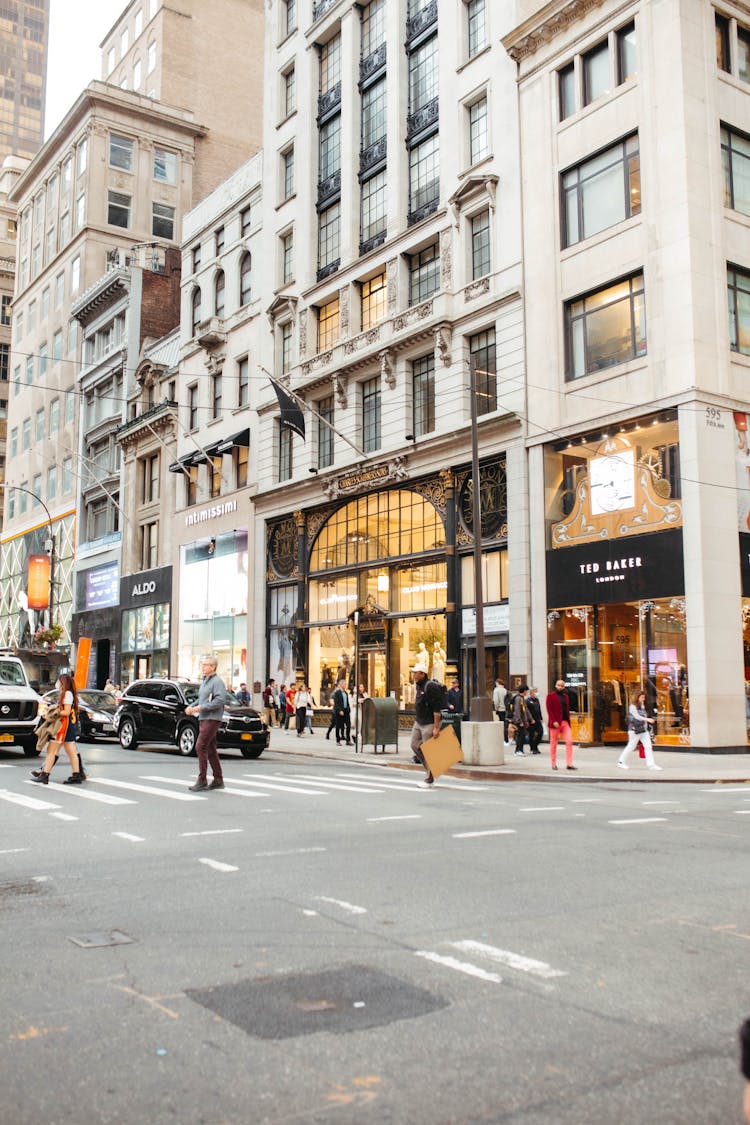 People Crossing The Road Near The Storefronts