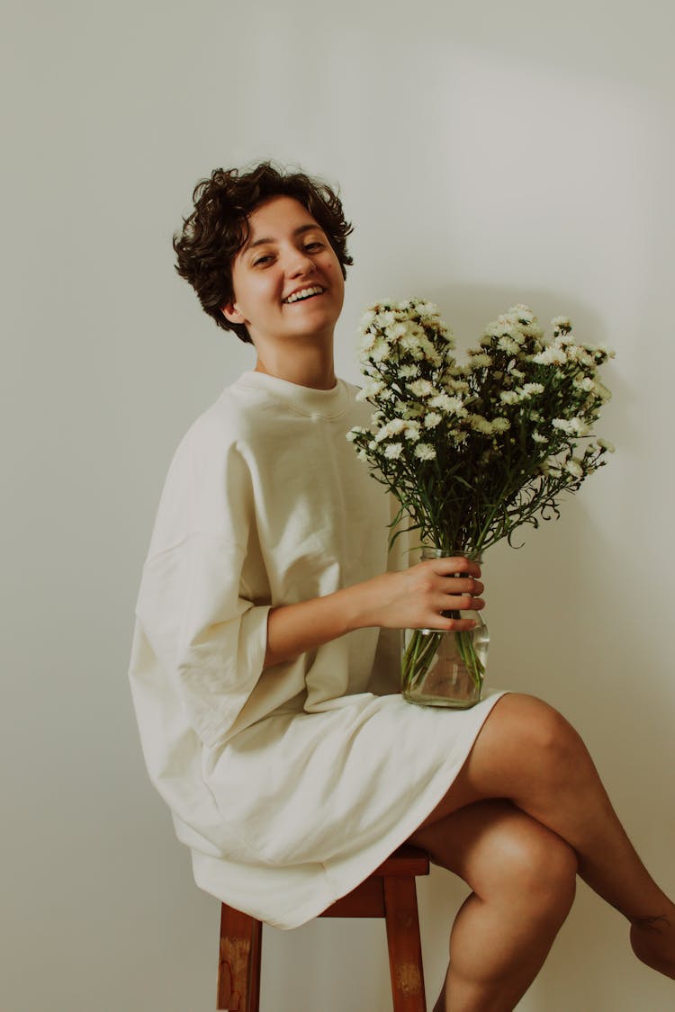 Smiling Woman With Short Hair Posing With A Bouquet On A Chair