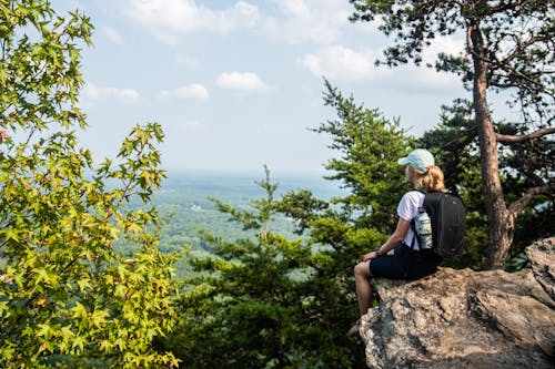 Woman in White Shirt Sitting on a Rocky Cliff