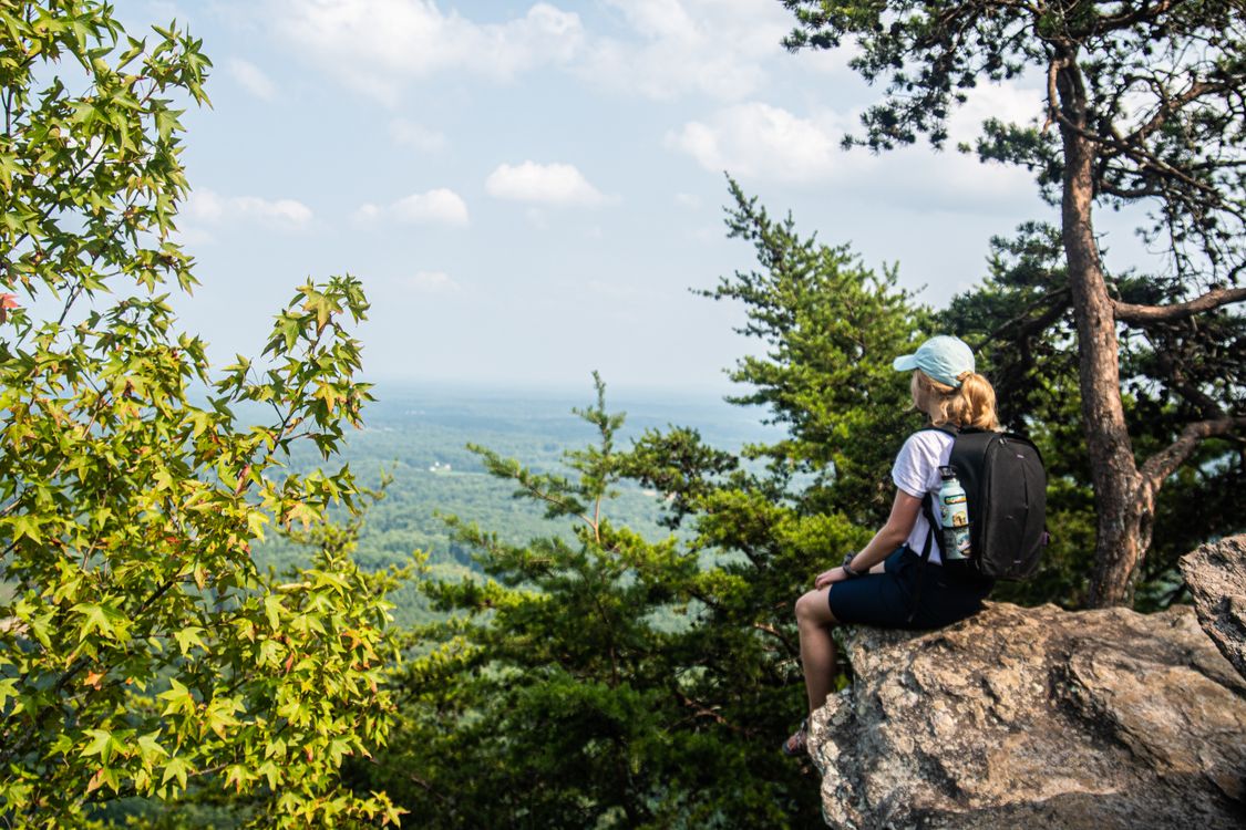 Woman in White Shirt Sitting on a Rocky Cliff · Free Stock Photo