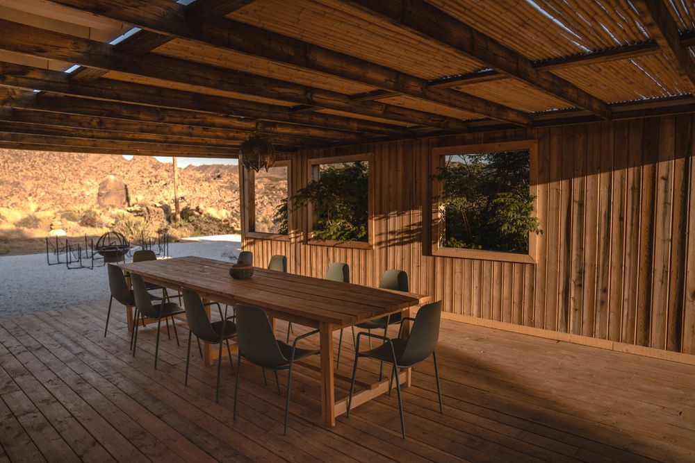 Terraza editorial de lodge con mesa de madera y ventanales abiertos al desierto