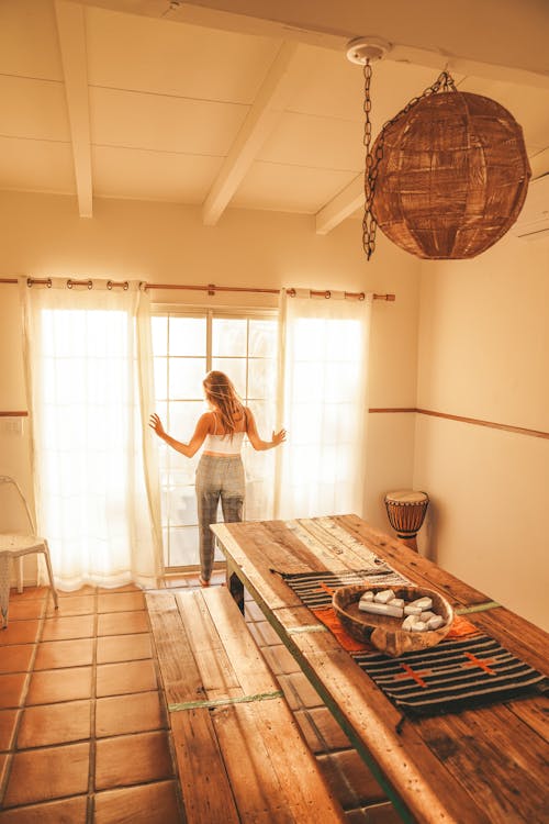 Woman Pulling Curtains in Kitchen 