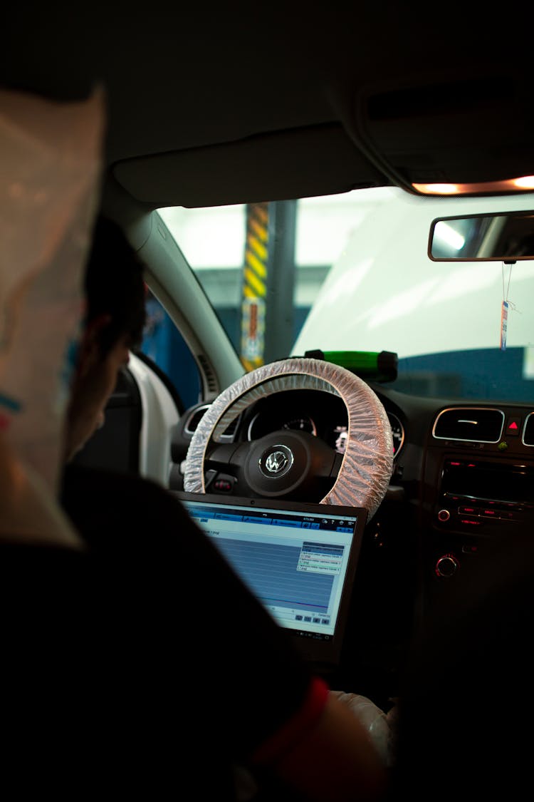 Person Using A Laptop While Sitting On A Driver's Seat 