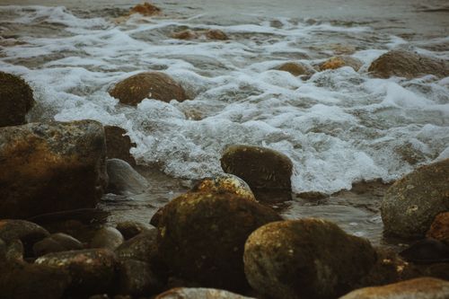Free Serene coastal scene with rocks and gentle waves creating sea foam. Stock Photo