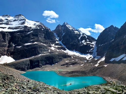 Free A breathtaking view of snow-capped mountains surrounding a turquoise lake under a bright blue sky. Stock Photo