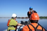 Man in Green and Orange Jacket Wearing White Helmet Riding on Orange and Black Kayak during