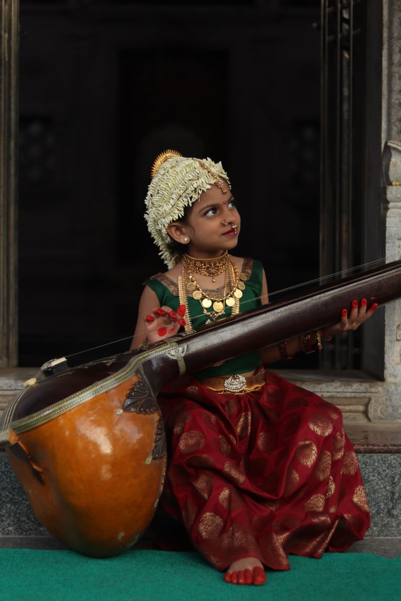 Young girl in traditional attire playing the veena