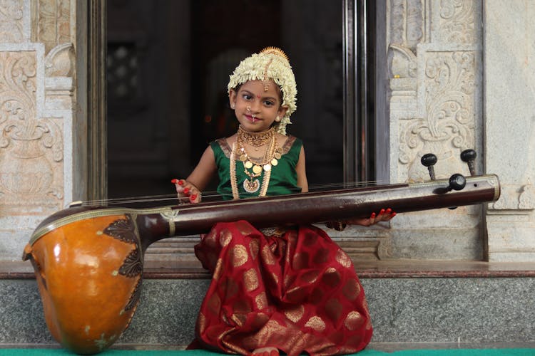 Girl Child In Traditional Costume With Musical Instrument