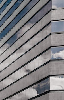 Sleek glass facade of a modern building in Colombia with sky reflections.