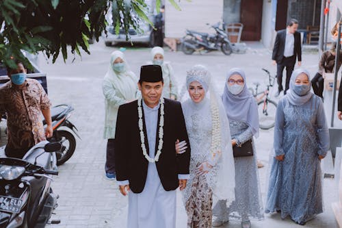 A Man in Black Suit Jacket Beside Woman in White Hijab