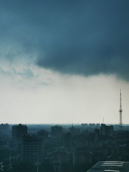 A dramatic city skyline silhouetted under dark, ominous clouds enhancing urban gloom.
