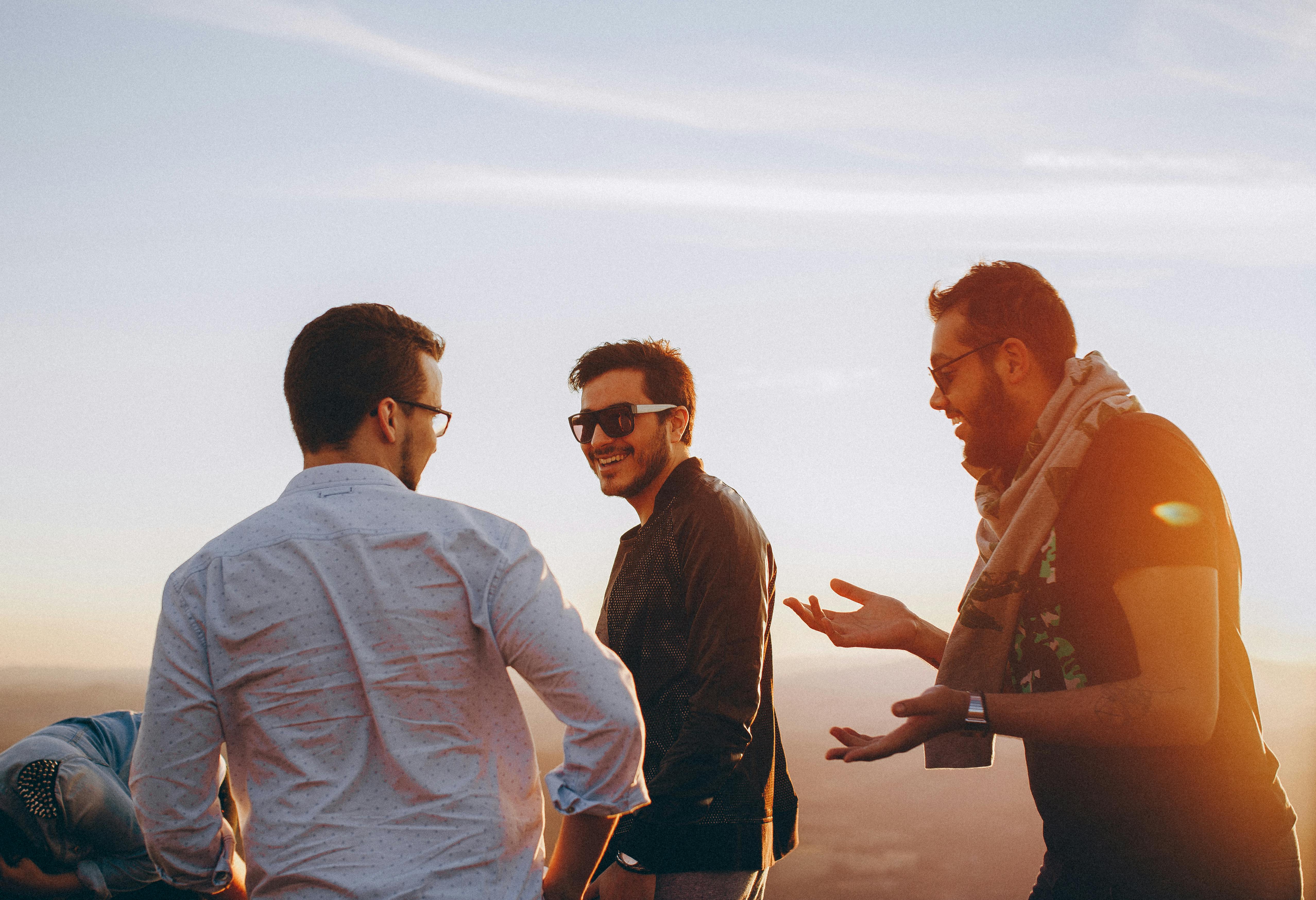 three men standing while laughing