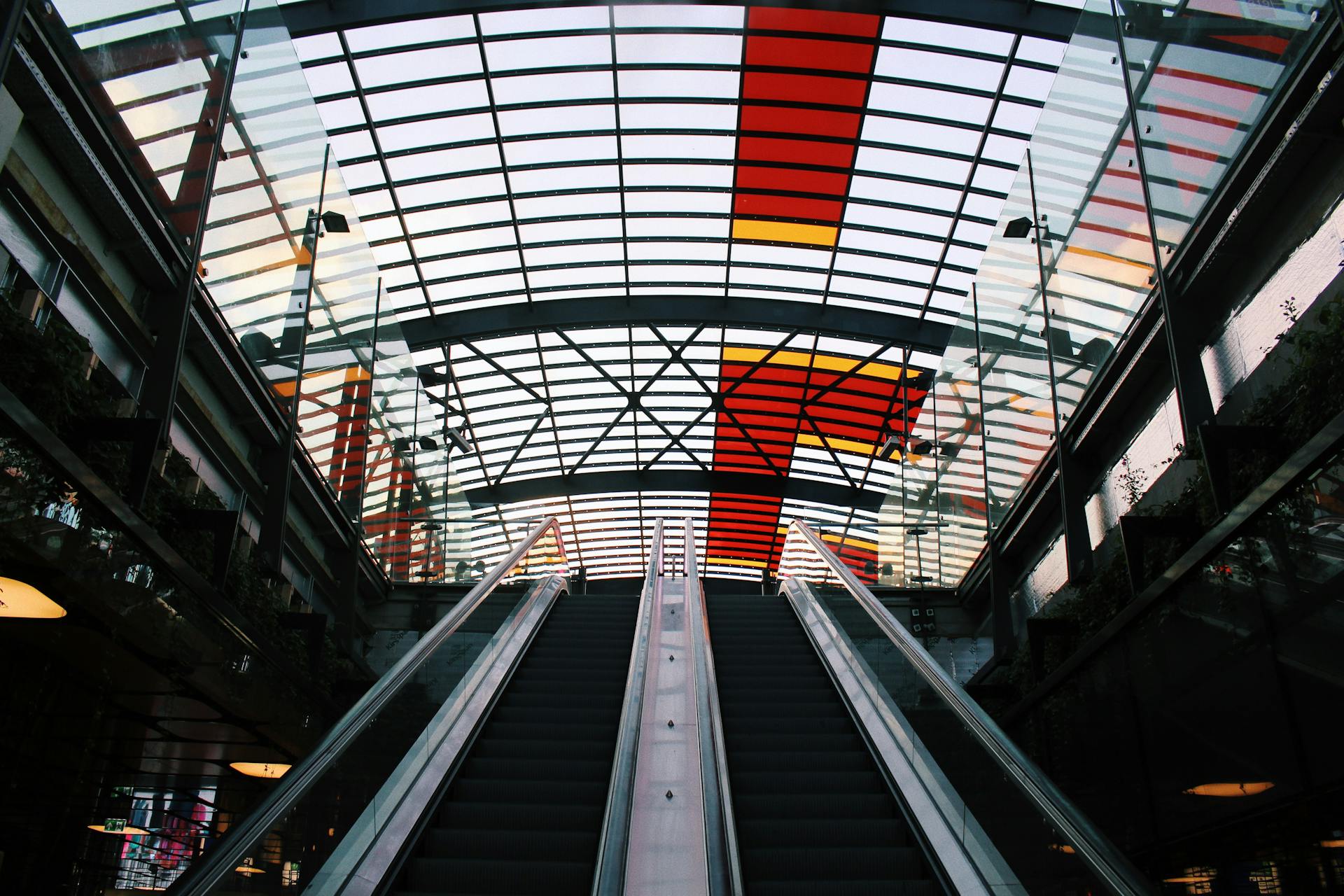 Futuristic escalator and glass roof design in Amsterdam train station.